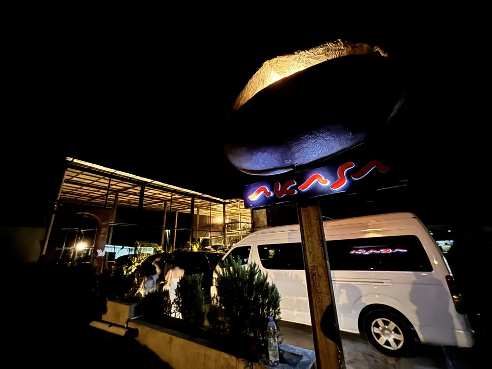 The lit Akasa Specialty Coffee entrance sign at night in Kintamani, Bali