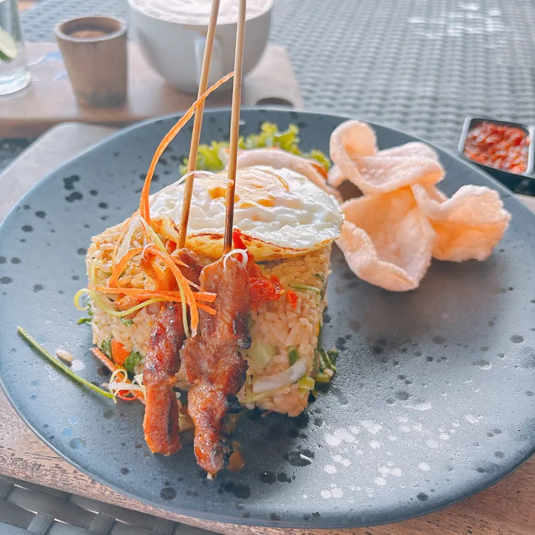A plate of Indonesian food with rice and satay served at a caldera-view restaurant in Kintamani, Bali