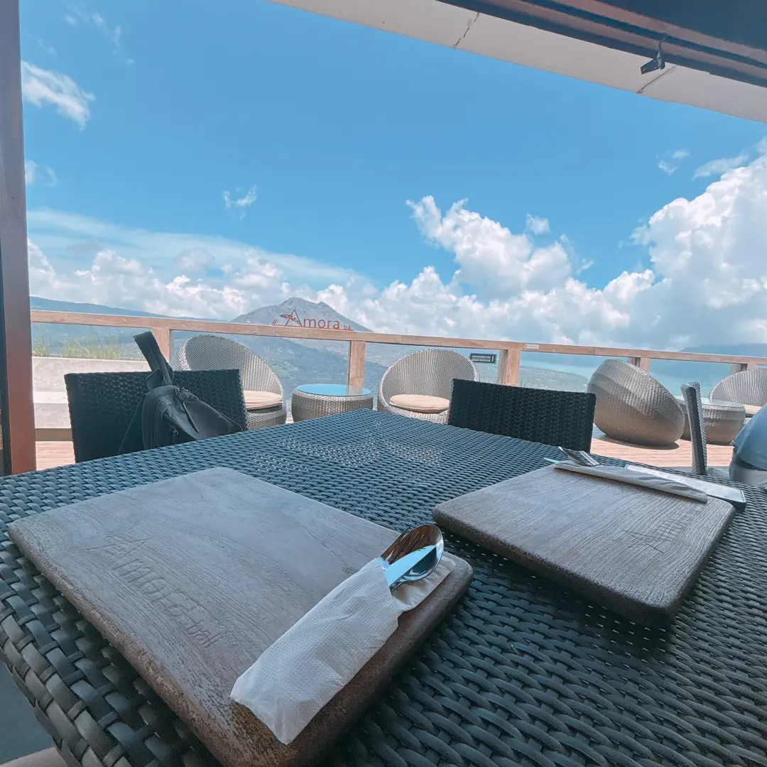 The open-air terrace and wooden tables at Amora Kintamani Restaurant looking out over Mount Batur, Bali