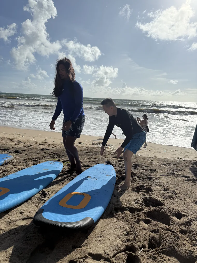 A surf instructor coaching a student through the pop-up stance on the sand at Kuta Beach, Bali