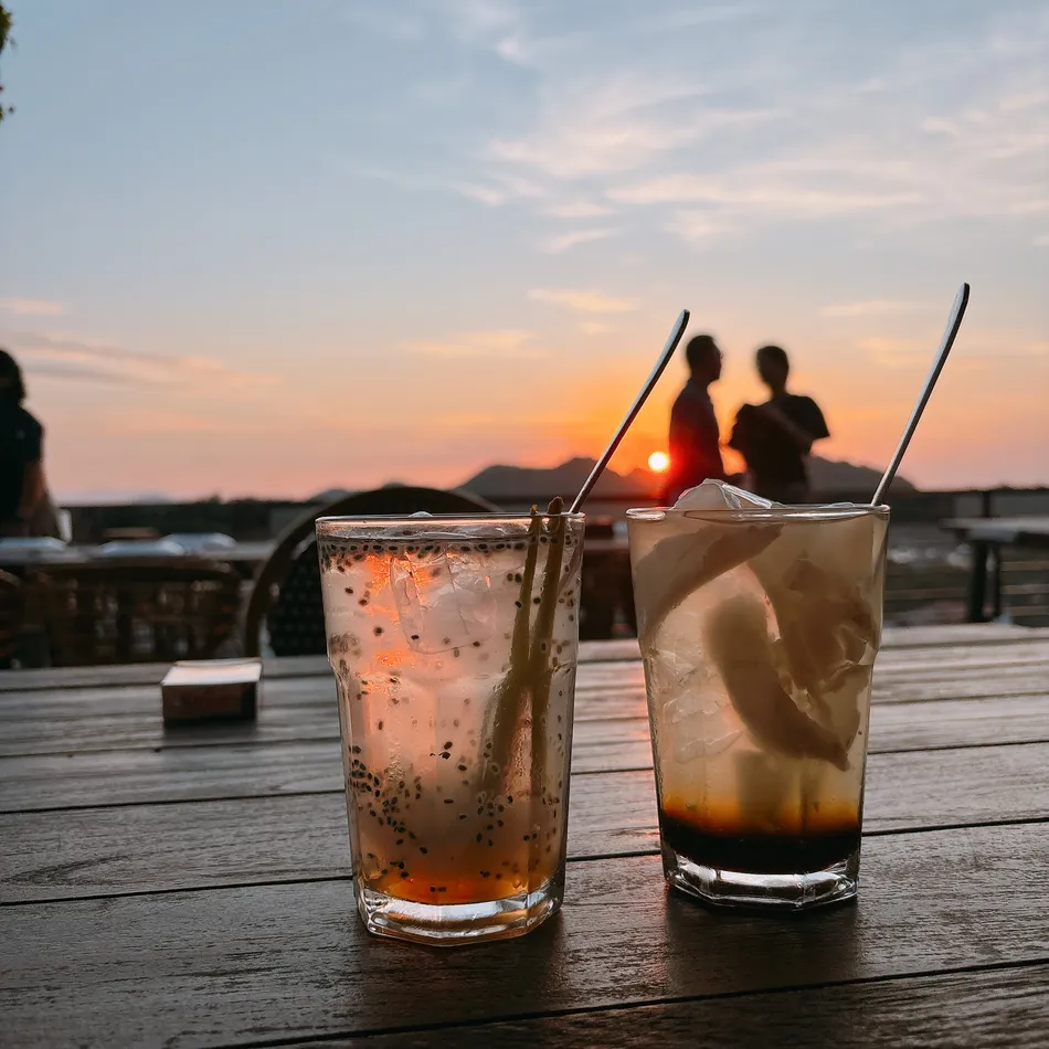 日落時 Taman Laut Handayani Seafood Restaurant 桌上的兩杯飲料，背景是兩個剪影