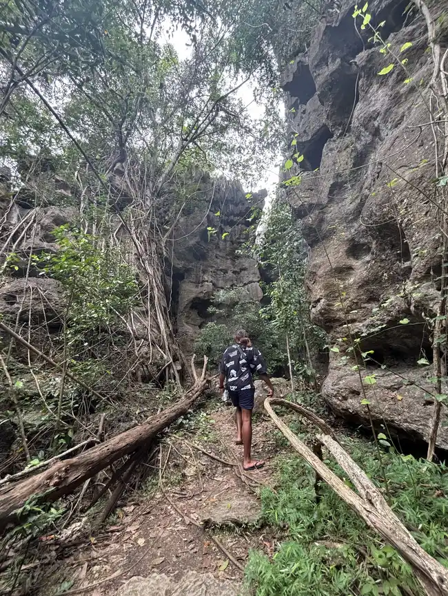 A visitor walking into the narrow rock canyon leading to Mirror Stone Cave (Goa Batu Cermin) near Labuan Bajo