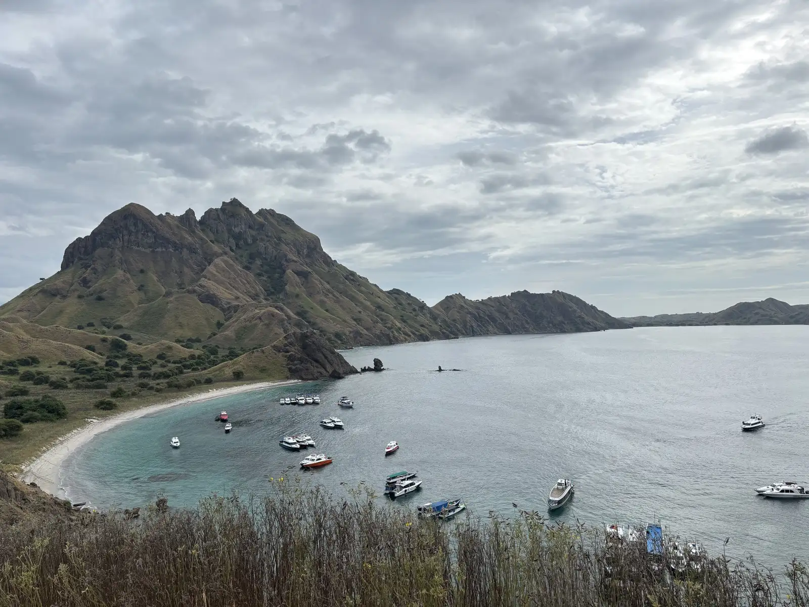 The famous three-bay viewpoint from the top of Padar Island in Komodo National Park, with tour boats anchored in the turquoise water below