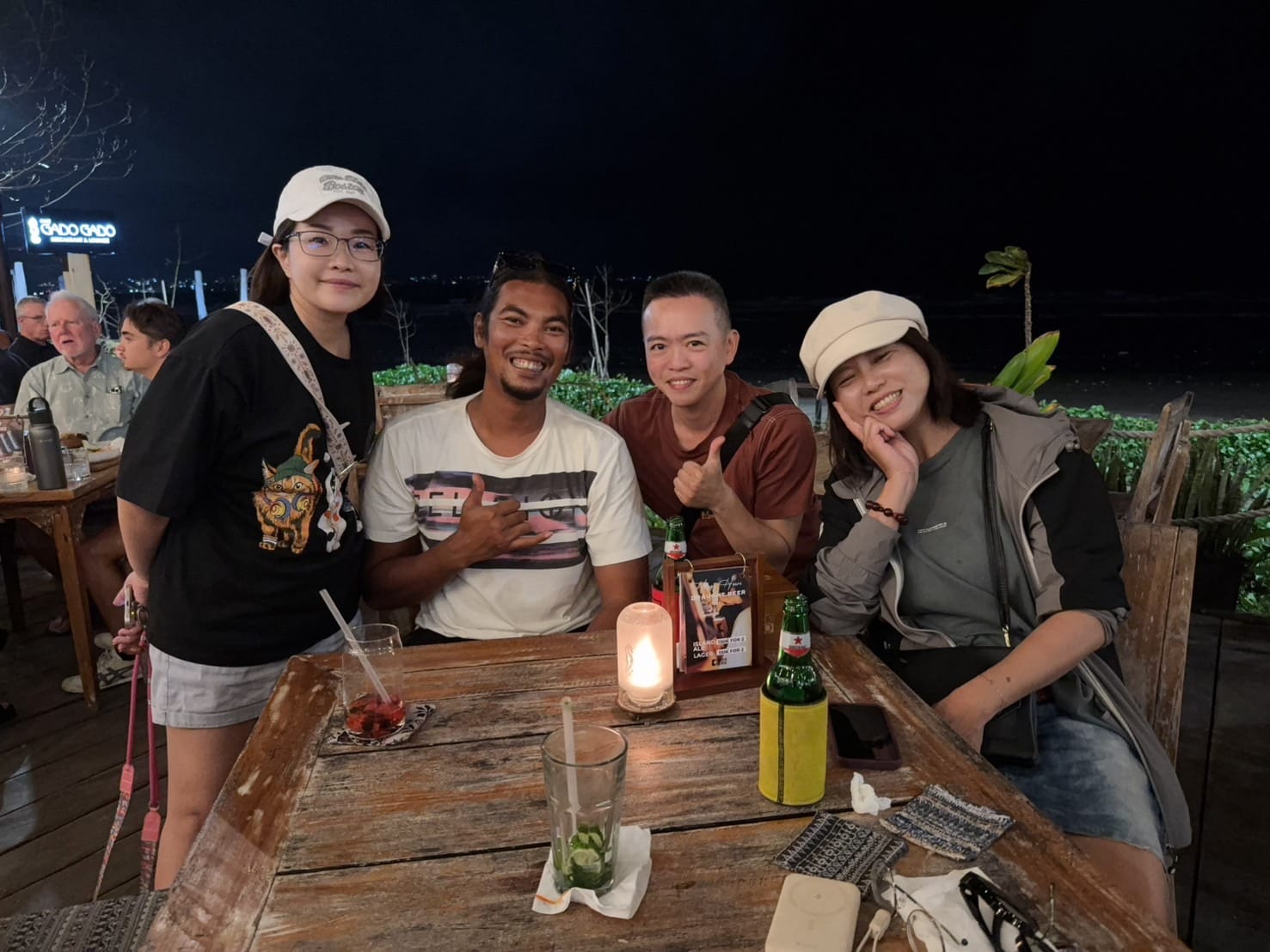 Andrew with travellers at a candle-lit beachfront table on Kuta Beach at night