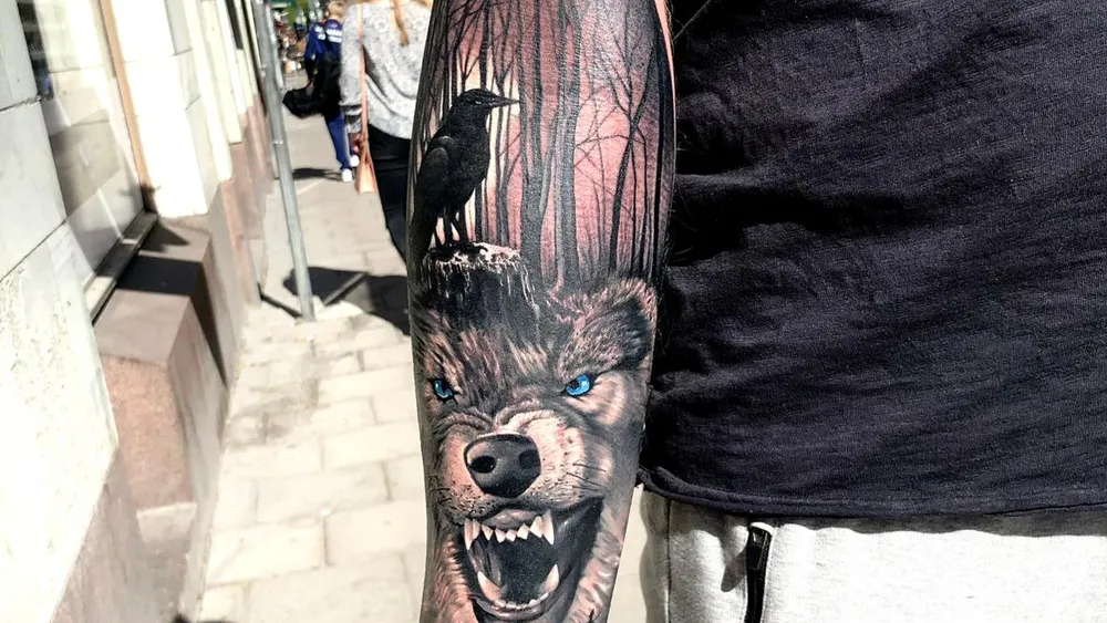 Black and grey realistic wolf with dark forest and raven forearm tattoo, Kuta Bali