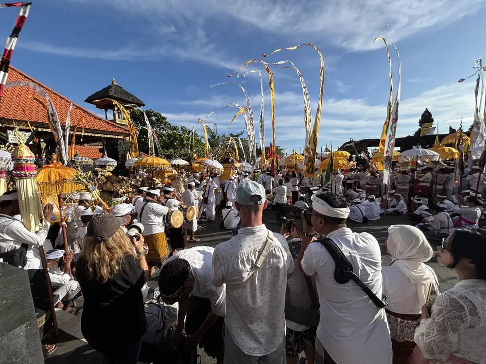 A Melasti purification procession dressed in white with ceremonial umbrellas and banners at the Tanah Lot sea temple before Nyepi, Bali