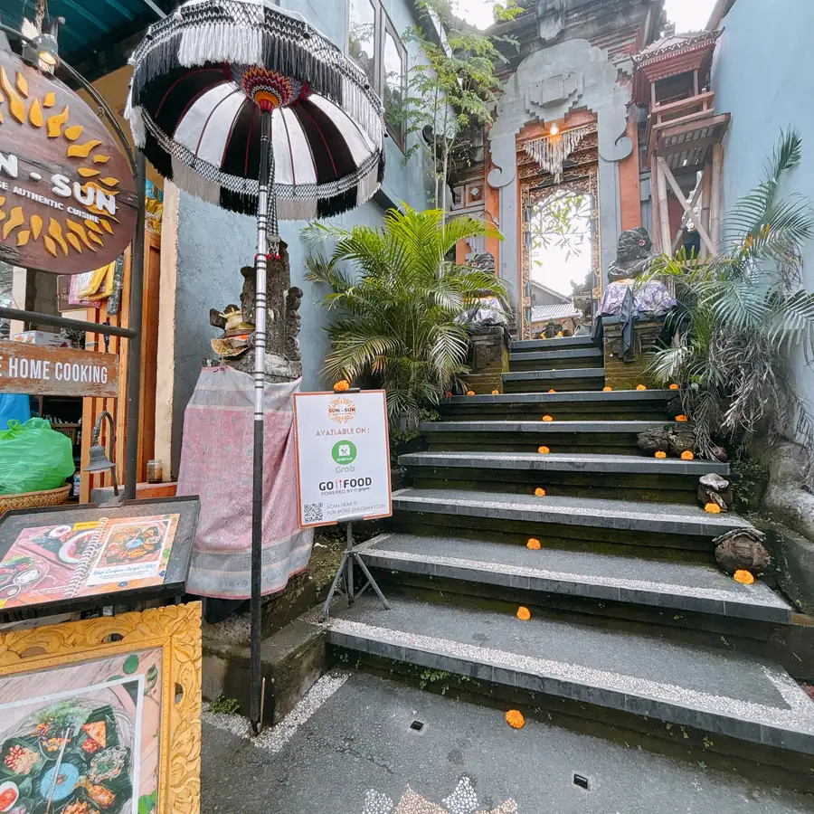 The entrance to SUN SUN warung in Ubud, Bali, with an umbrella and menu boards