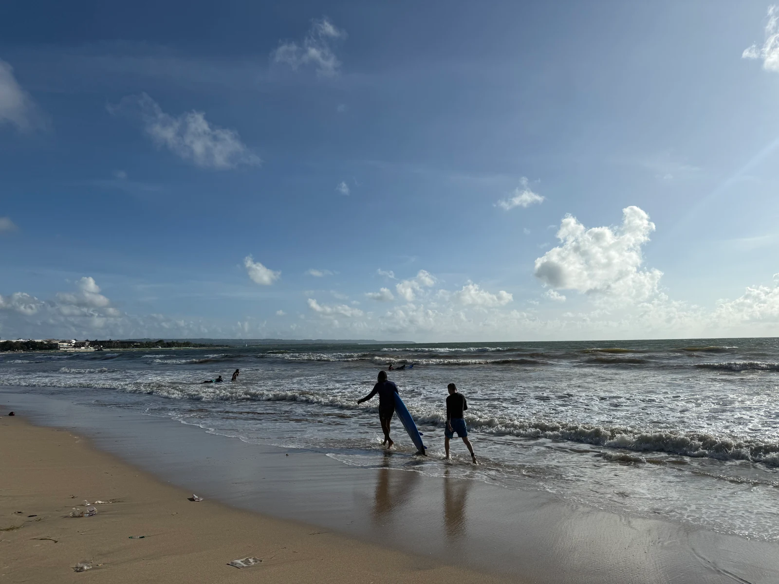 A surf instructor and student walking into the shallows for a beginner lesson on a Bali beach