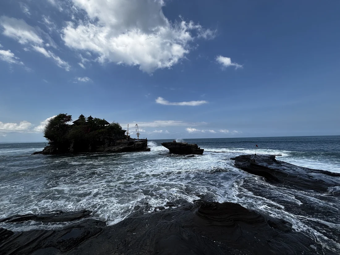 The Tanah Lot temple rock with waves washing over the rock shelf in front of it at high tide, Bali