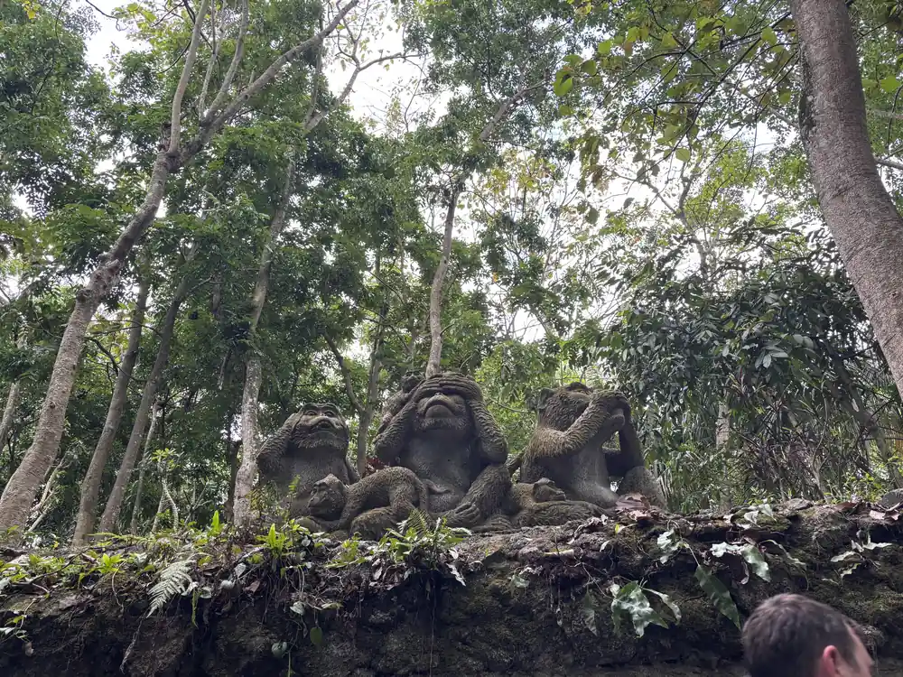 Mossy stone monkey statues along a jungle path in the Sacred Monkey Forest, Ubud, Bali