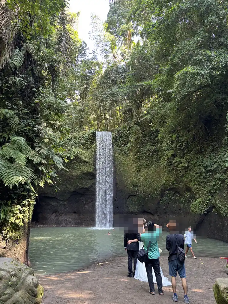 Tibumana Waterfall near Ubud, a single-tier fall dropping into a wide turquoise pool with visitors at the edge