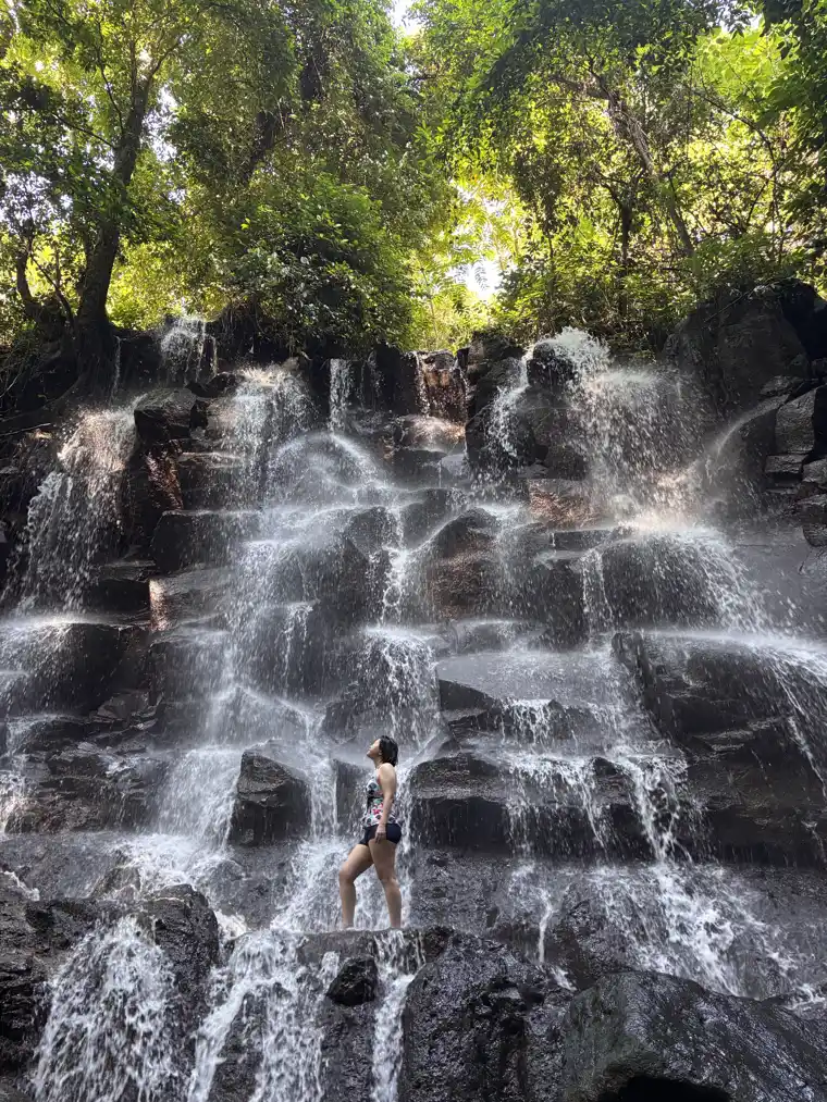 Kanto Lampo Waterfall near Ubud, water stepping down a wide face of black volcanic rock into a shallow pool